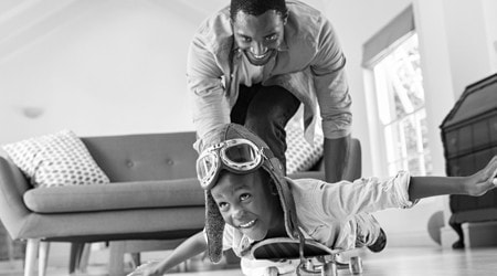 Adult and kid playing airplane in livingroom