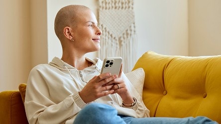 person sitting on couch holding phone smiling