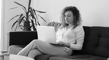 Young woman sitting on couch with laptop