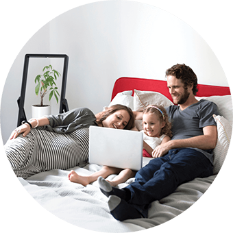 A family watches a movie together on a laptop in a bed