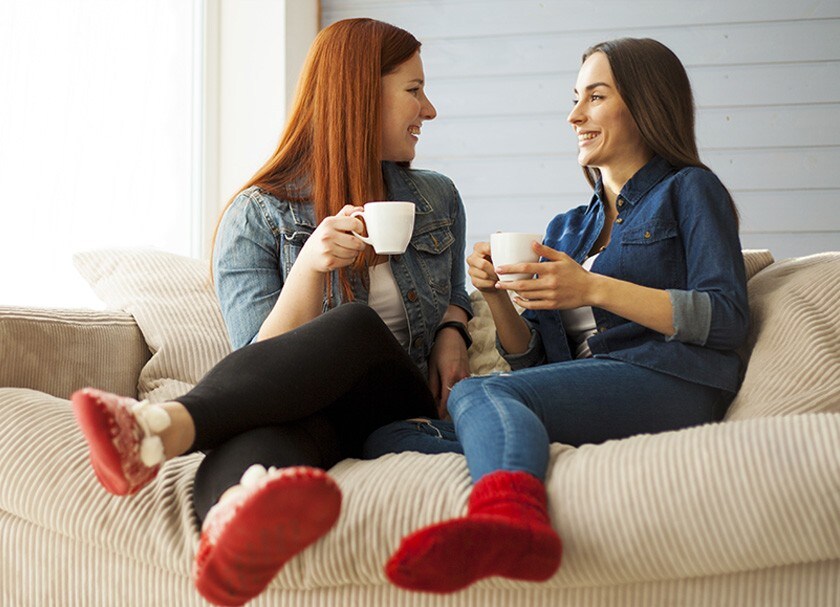 Two women chatting with coffee mugs