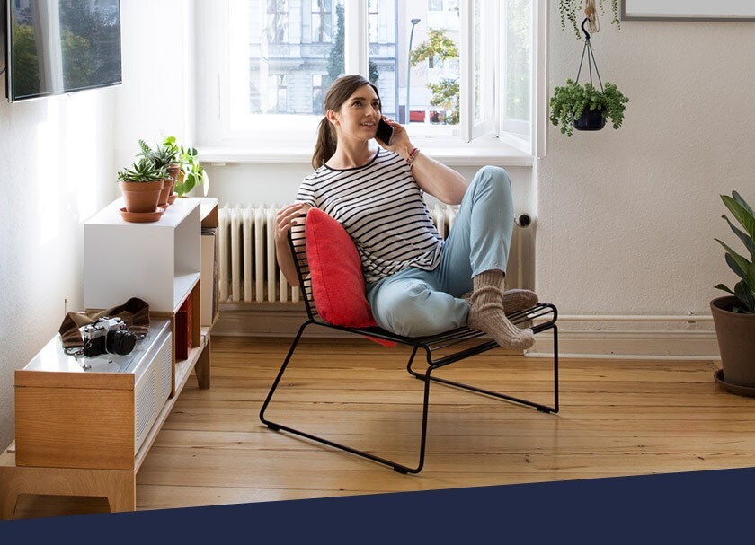 Woman at home sitting on chair talking on cellphone