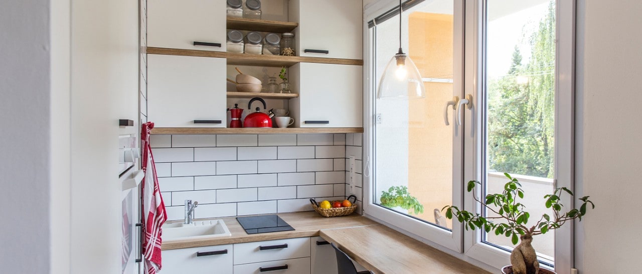 An area of a tiny home that includes a kitchen, a table and large windows to a patio