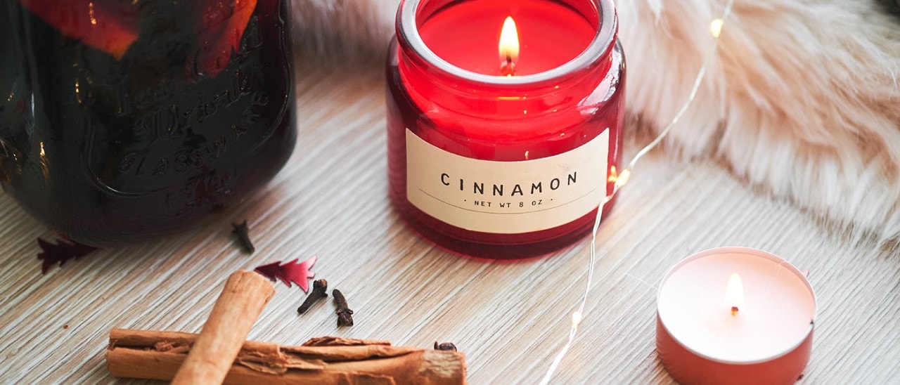 A cozy setting with cinnamon candles and cinnamon sticks.