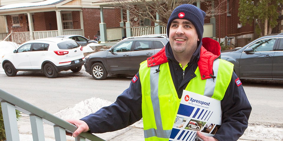 Canada Post worker delivering an envelope