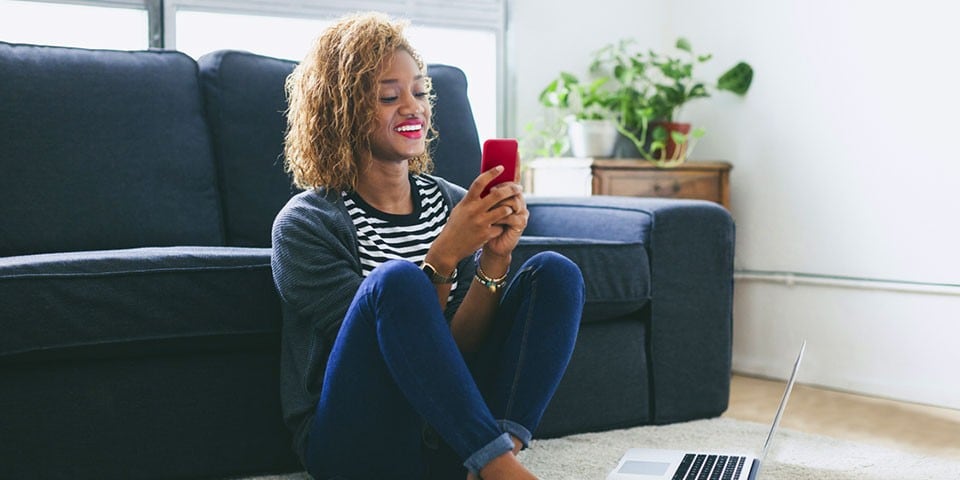 Woman sitting on the floor and using a smartphone